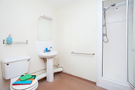 A bathroom with a toiler, shower, sink and mirror.