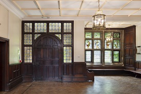 A hallway with wooden doors and panels and stained glass windows.