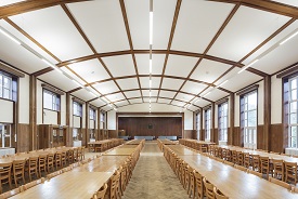 A large dining hall with four rows of tables and seats all around them.