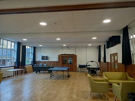 A large room with a pool table, air hockey table and comfy seats.