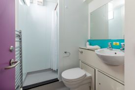 A bathroom with a toilet, shower, sink and mirror.