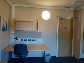 A desk with a chair and shelves above. Door to the far right of the room.