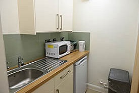 A kitchen with a sink, fridge, microwave and cupboards.