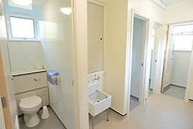 A room with several toilets cubicles, and sink and a mirror.