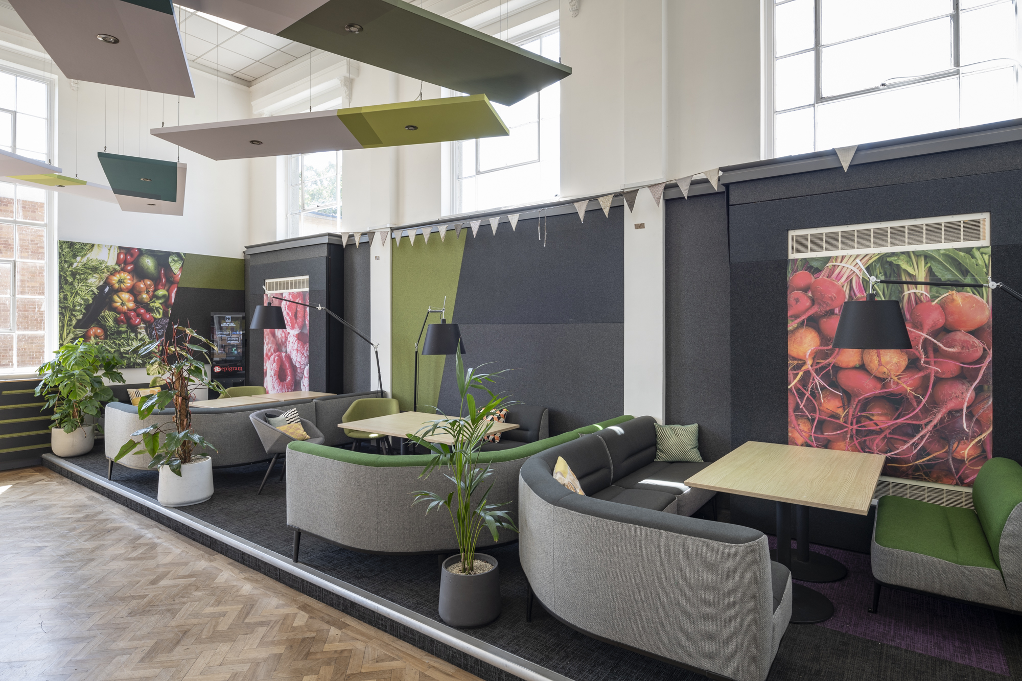 A small platform with three square tables each surrounding by curving sofa chairs. There a number of pot plants.