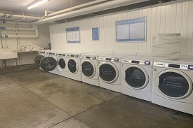 A room with a row of eight washer dryers against one wall.