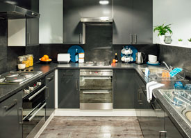 Shared kitchen area, showing two cookers and hobs, a sink, storage cupboards, a toaster and kettle