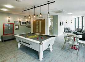 Communal area with pool table, a small table and four chairs, and three sofas