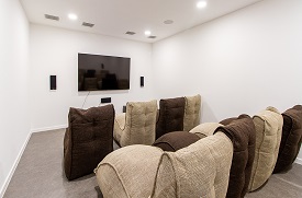 A room with two rows of four armchairs facing a television screen on the wall.