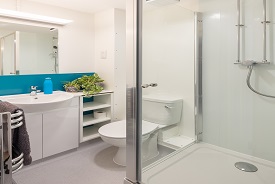 A bathroom with a toiler, shower cubicle, sink and mirror.