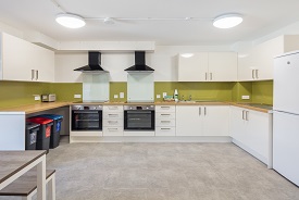 A kitchen with two ovens and hobs, three recycling bins, a fridge freezer, and lots of cupboards and drawers.