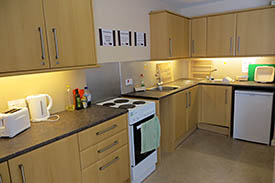 A kitchen with an oven and hob, a fridge, and lots of cupboard and drawers.