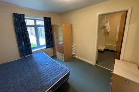 A bedroom with a bed to the left, window in the rear of the picture, cupboard to the right of the window and en suite in the rear right of the photo.