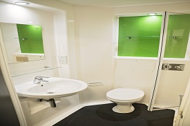 A bathroom with a toilet, sink, mirror and shower cubicle.