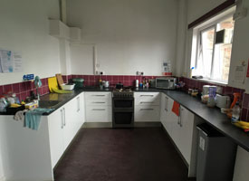 A kitchen with an oven and hob, a sink, a microwave and several cupboards and drawers.