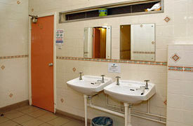 A tiled room with two sinks with mirrors over them.