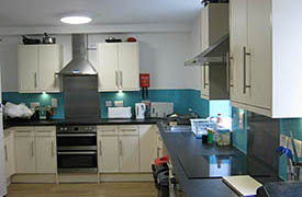 A kitchen with two ovens and hobs, a sink and lots of cupboards and drawers.