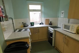 A kitchen with a hob, microwave, sink and utensils.
