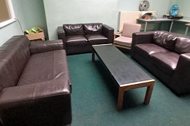 A room with 3 leather sofas and a coffee table in the middle