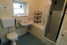 A bathroom with a singular shower, sink and toilet to the right.