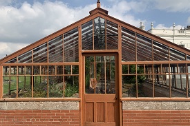 A greenhouse with red brick walls and a wooden frame.