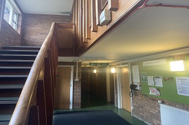 A hallway with a staircase and wooden bannister leading up to another floor.