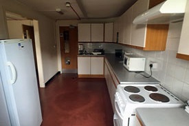 A kitchen with an oven and hob, a fridge, a microwave and lots of cupboard and drawers.