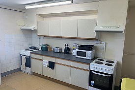 A kitchen with two ovens and hobs, a microwave and several cupboards.