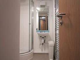 A bathroom with a sink, mirror and shower cubicle.