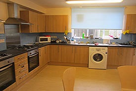 A kitchen with two ovens and hobs, two sinks, a washing machine and lots of cupboards and drawers.