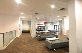 A large room with two sofas around a coffee table, a larger table with six chairs around it, a ping pong table, a pool table, and another sofa and two vending machines against the far wall.