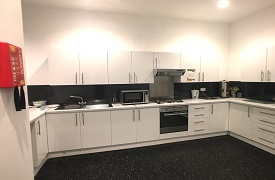 A kitchen with an oven and hob, a sink, a microwave, and lots of cupboards.