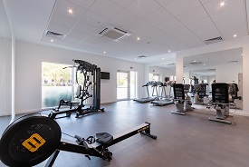 A room with a rowing machine, a weight machine, two treadmills and two exercise bikes.
