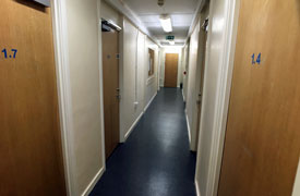 View down the central corridor with several doors on the left and right hand side leading to bedrooms