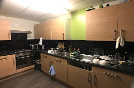 View of the communal kitchen, showing two sinks, a cooker and hob, storage units, a kettle anmd a toaster