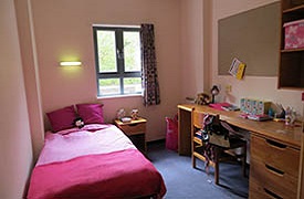 Bedroom showing single bed, bedside table, desk and chair, storage unit and shelves