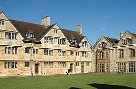Exterior view of Wills Hall, comprising of two large stone buildings located around a central grassed area. The sky is blue and students are walking and sitting around the grassed area