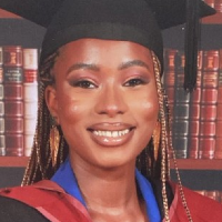 A black woman smiling and wearing a mortarboard.