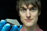 Tim Gregory holding up a meteorite to the camera