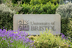 An image of the stone University of Bristol sign outside Royal Fort Garden surrounded by foliage