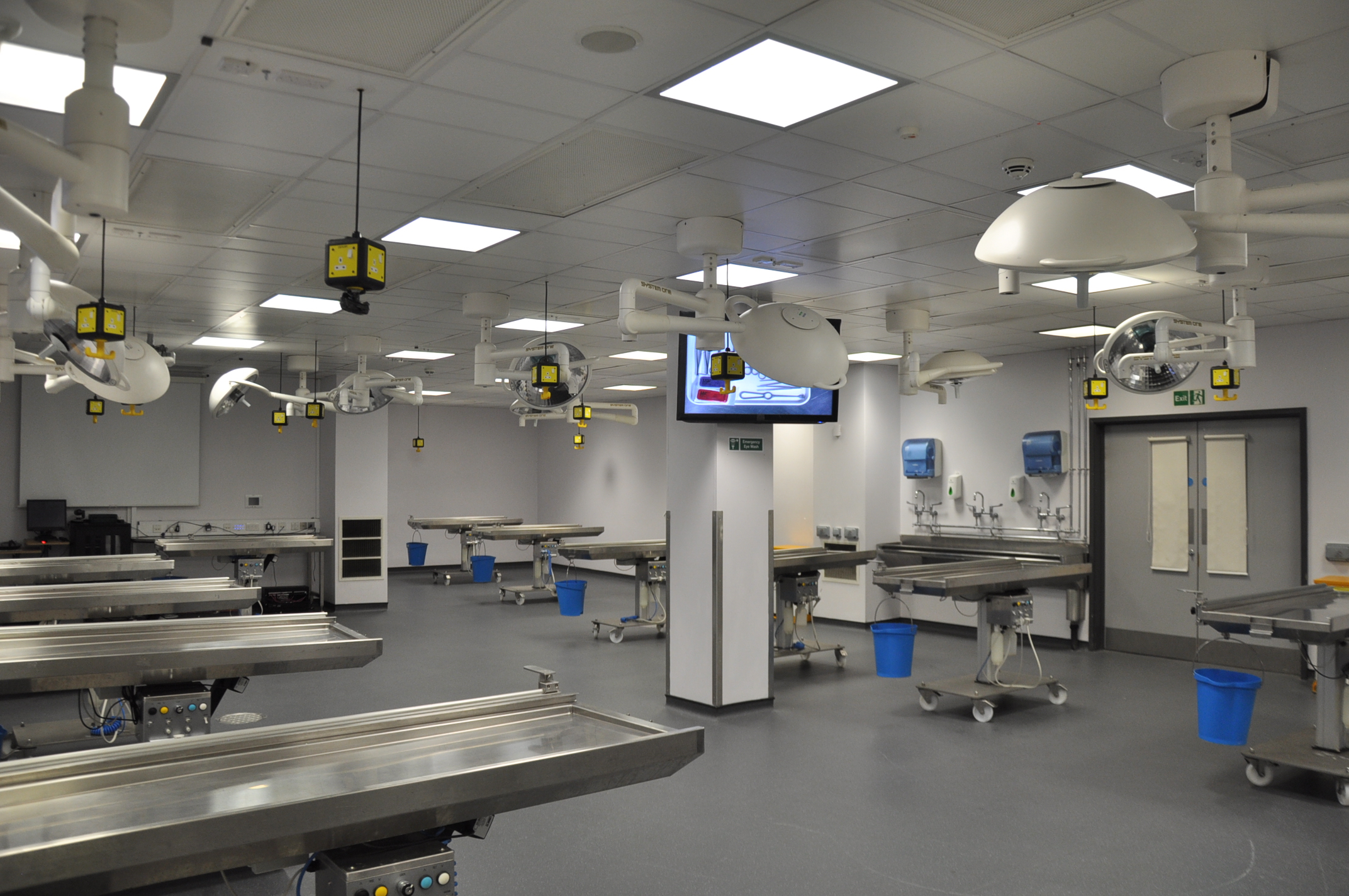 The Vesalius dissection room, a large empty lab set up with stainless steel dissection and specialist operating theatre lighting.