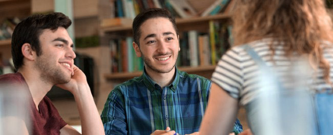 Three postgraduates chatting in library