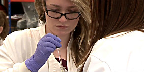 An undergraduate uses a pipette in a lab session