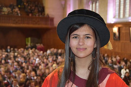 Mya Rose receiving her honorary degree stands with her back to the audience in the Great Hall in the Wills Memorial Building