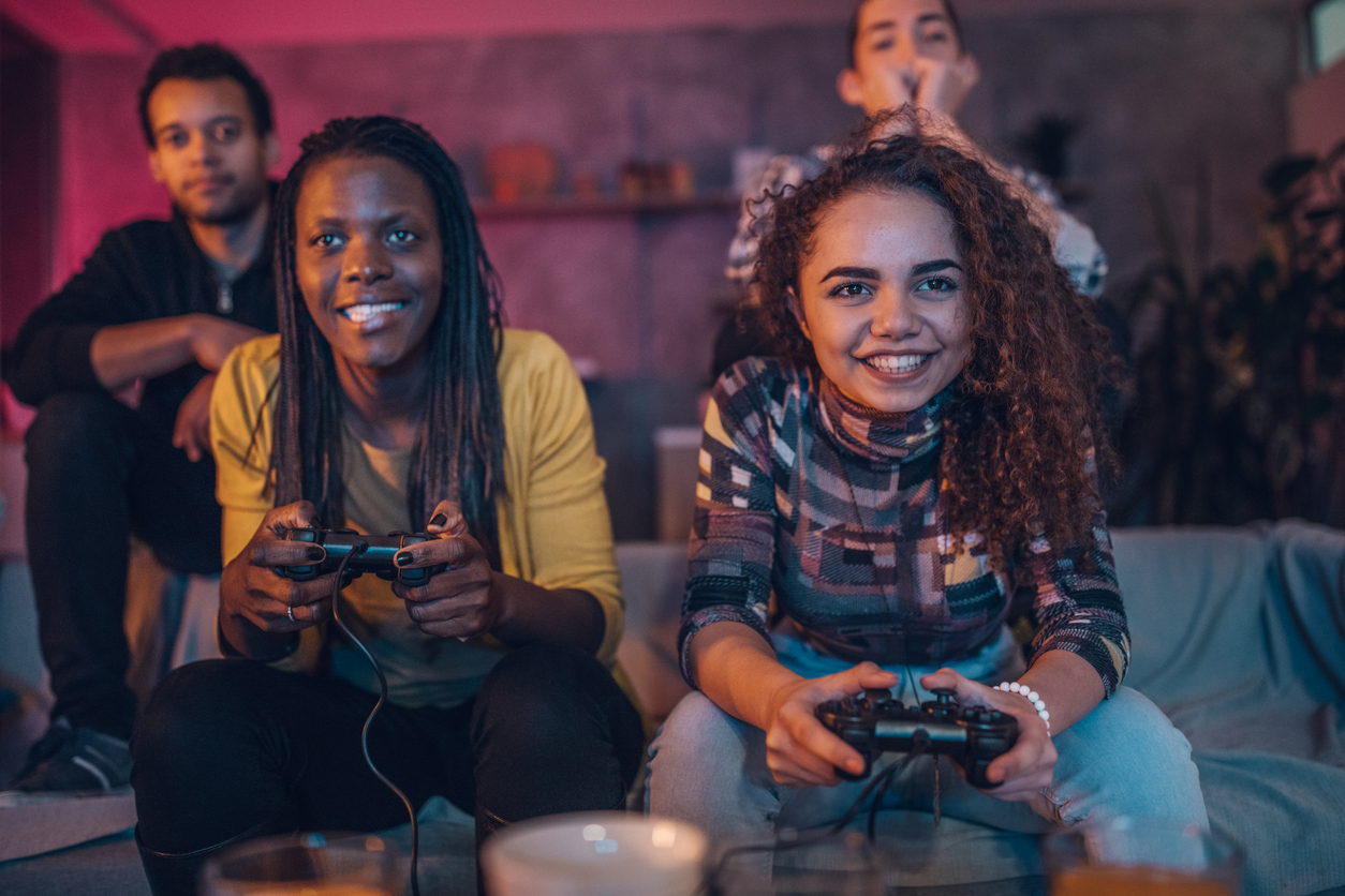 A group of four black heritage young adults play video games and laugh