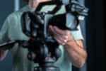 Close-up of a motion picture camera being operated by a person.