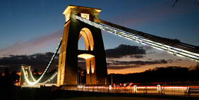 The iconic Clifton Suspension Bridge lit up at sunset. 