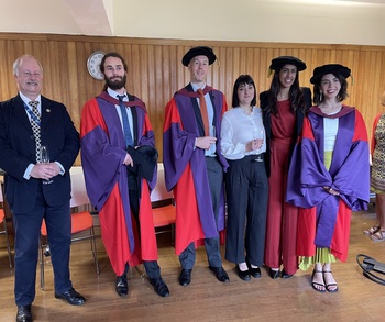 A group of BCI graduates in gowns, with Professor Ian Hamerton