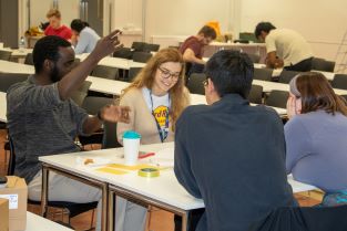 A team of four students sitting at a table discussing strategy for the BCI Egg Challenge competition