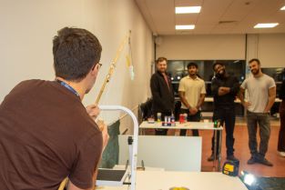 A student using a pole and lasers to accurately position their protected egg above the drop zone